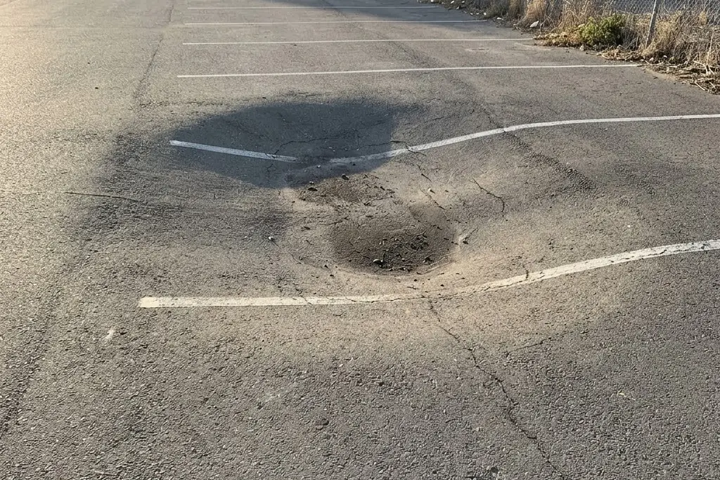 An area of asphalt that has settled below the surface around it